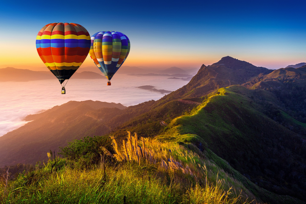 Paisaje de niebla matutina y montañas con globos aerostáticos al amanecer